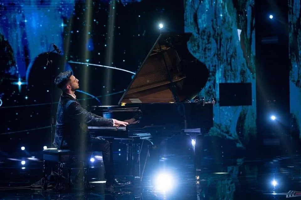 Albert Gugulan at the piano in a wide view of the stage.